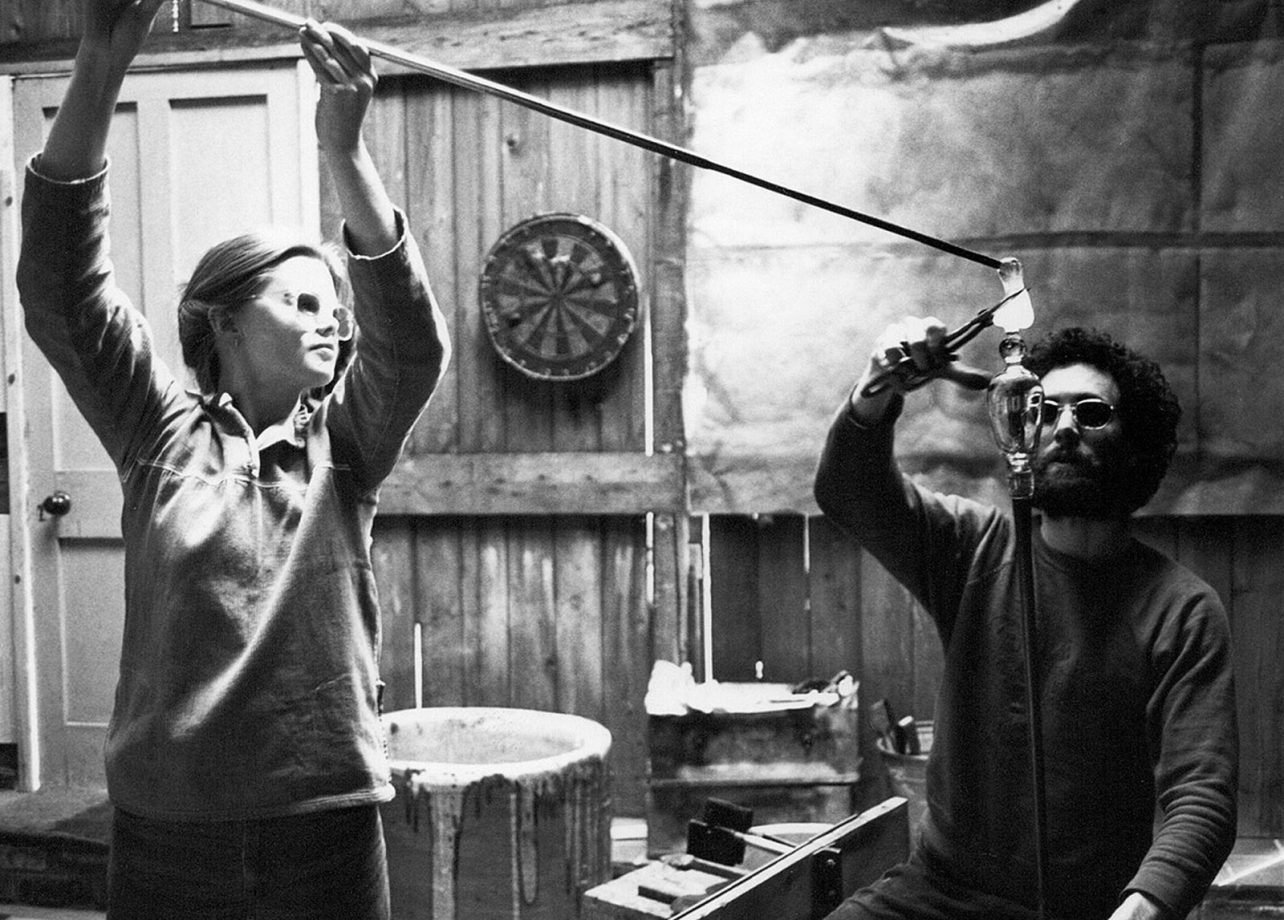 Black and white image of Annica and David in the workshop blowing glass